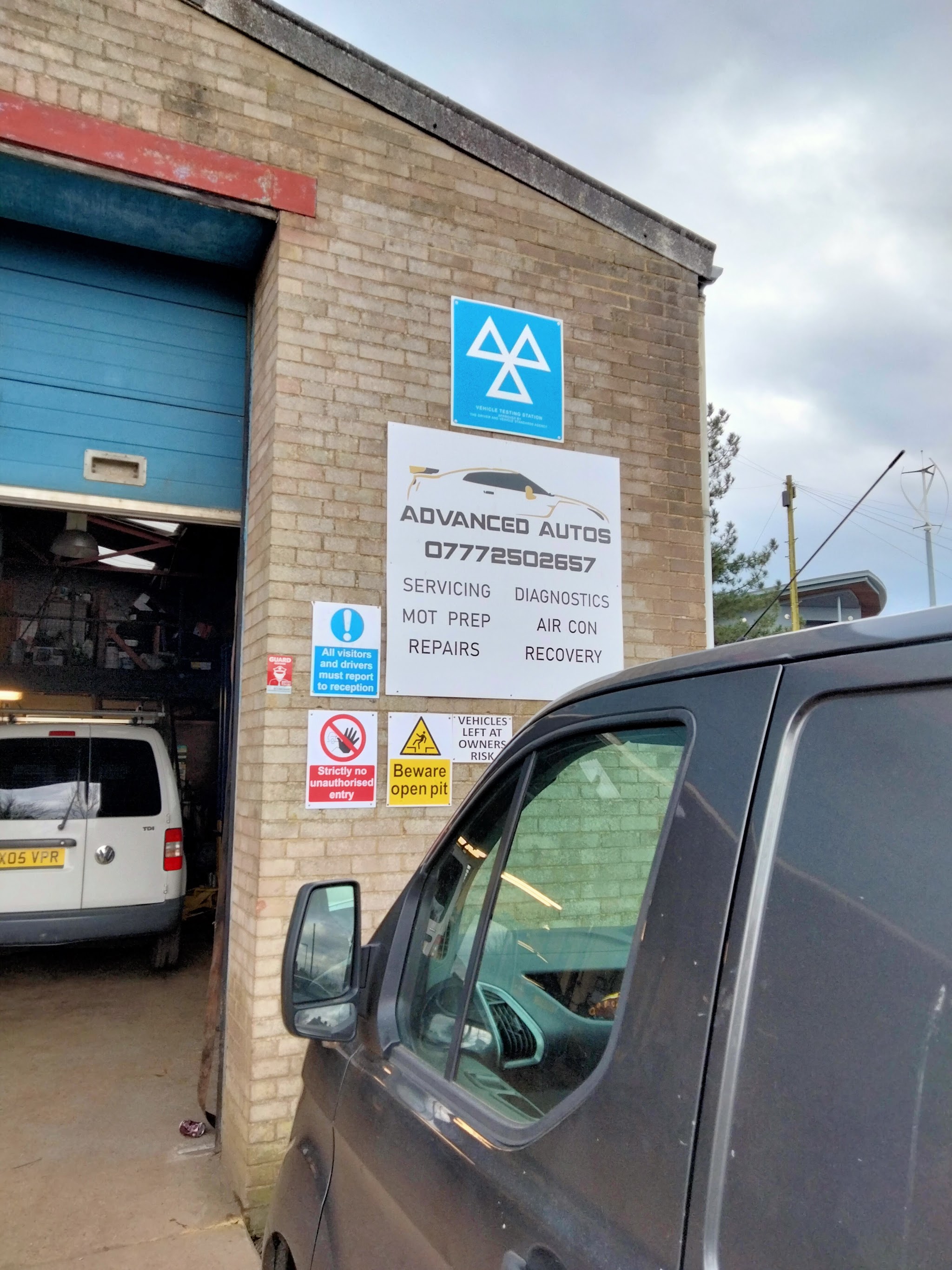 The workshop door with the Advanced Autos sign and the MOT sign beside it