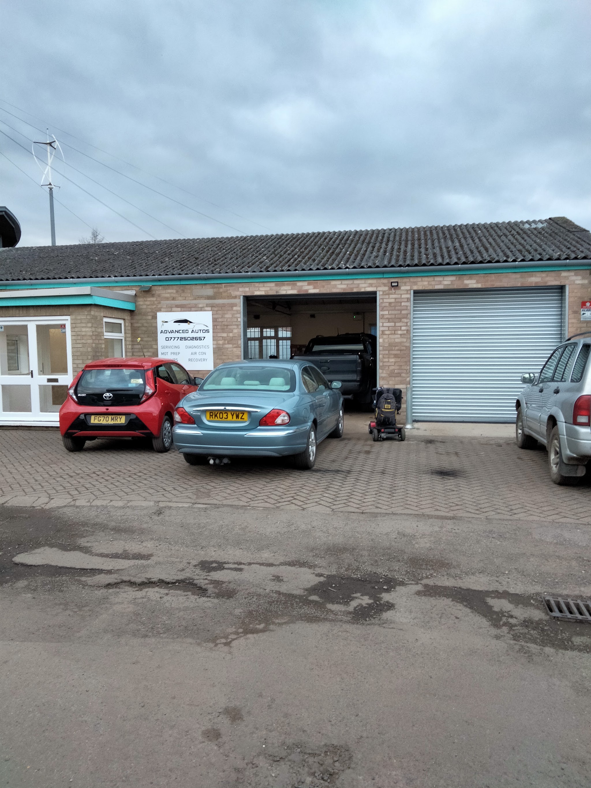 Cars parked on the front yard outside the workshop